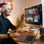 Homme avec un bonnet de Noël en télétravail faisant une fête virtuelle avec ses collègues